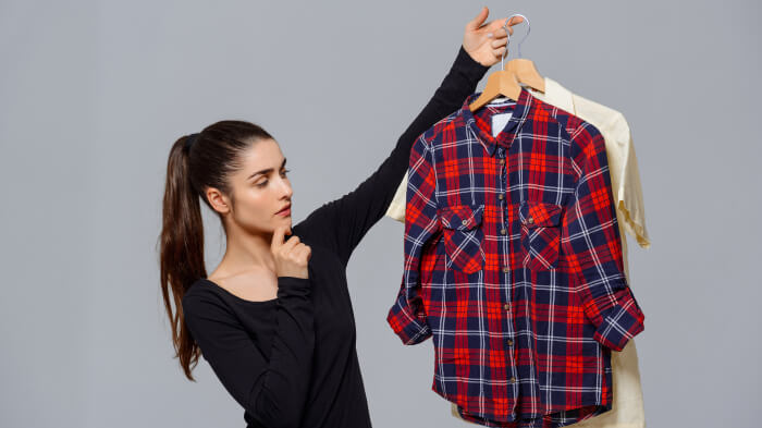 Women in full black T-shirt considering to choose between 2 shirts of color Red and white on a hanger