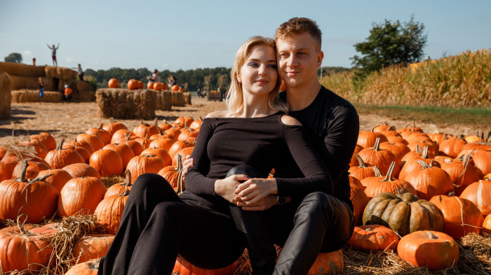 A Thanksgiving photo of a couple enjoying their date in a pumpkin patch.