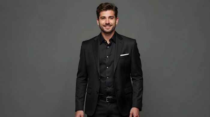 A photo of a man in a New Year outfit featuring a black shirt, blazer, and trousers.