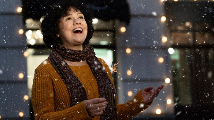 A photo of a woman in a winter outfit enjoying snowfall outdoors.