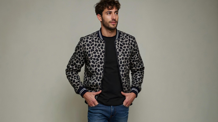 A photo of a man in a New Year outfit featuring a printed bomber jacket with slim-fit jeans. 