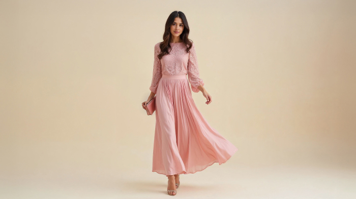 A photo of a woman in a blush pink lace blouse with a flowy pleated skirt, heels, and matching clutch. 