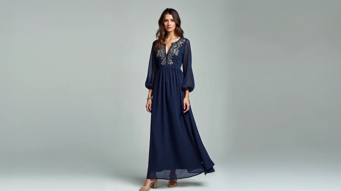 A photo of a woman in a navy blue long-sleeve maxi dress with delicate embroidery and low block heels.