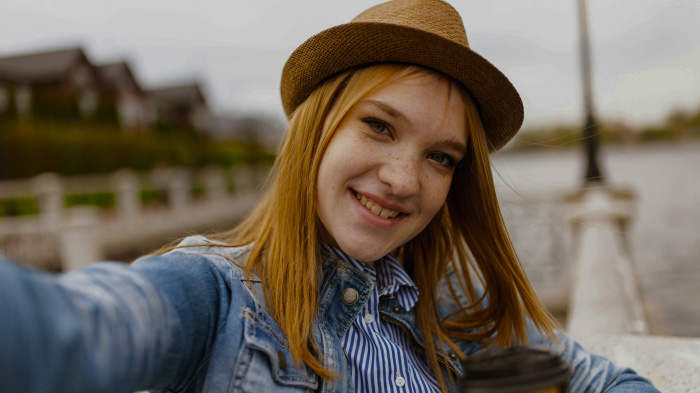 An outdoor selfie of a woman with poor lighting and unbalanced colors.